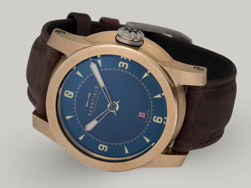 Best bronze Watches, the Schofield Beater Raw Bronze The B3 ✦ Raw Bronze wristwatch with a raw bronze case, blue dial, and tan hour markers with a numerals at 3,6,9 and 12. A small Sign-of-Life seconds hand can be seen in the centre.