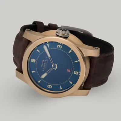 Best bronze Watches, the Schofield Beater Raw Bronze The B3 ✦ Raw Bronze wristwatch with a raw bronze case, blue dial, and tan hour markers with a numerals at 3,6,9 and 12. A small Sign-of-Life seconds hand can be seen in the centre.