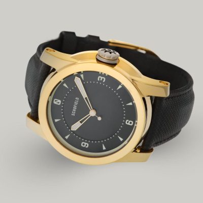 A polished gold-plated Treasure Watch ✦ Gold with a black leather strap. This treasure watch features a black minimal dial with Super-LumiNova markings and hands, including numerals at 3, 6, 9, and 12.