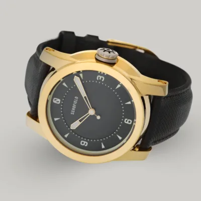 Gold treasure watches by Schofield A polished gold-plated Treasure Watch ✦ Gold with a black leather strap. This treasure watch features a black minimal dial with Super-LumiNova markings and hands, including numerals at 3, 6, 9, and 12.