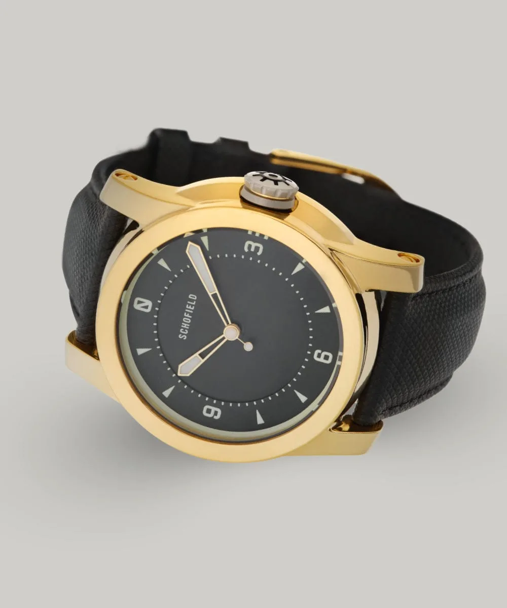 A polished gold-plated Treasure Watch ✦ Gold with a black leather strap. This treasure watch features a black minimal dial with Super-LumiNova markings and hands, including numerals at 3, 6, 9, and 12.