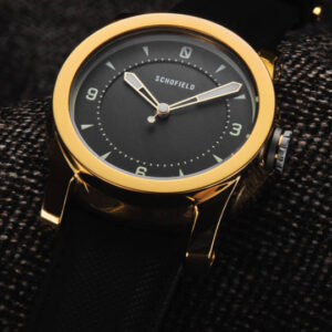 British made Schofield watches. The gold Treasure Watch shown against a brown background.