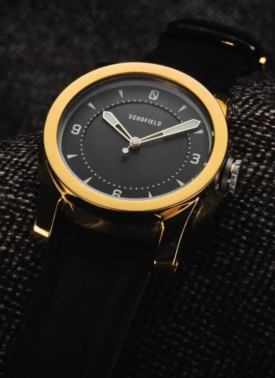 British made Schofield watches. The gold Treasure Watch shown against a brown background.