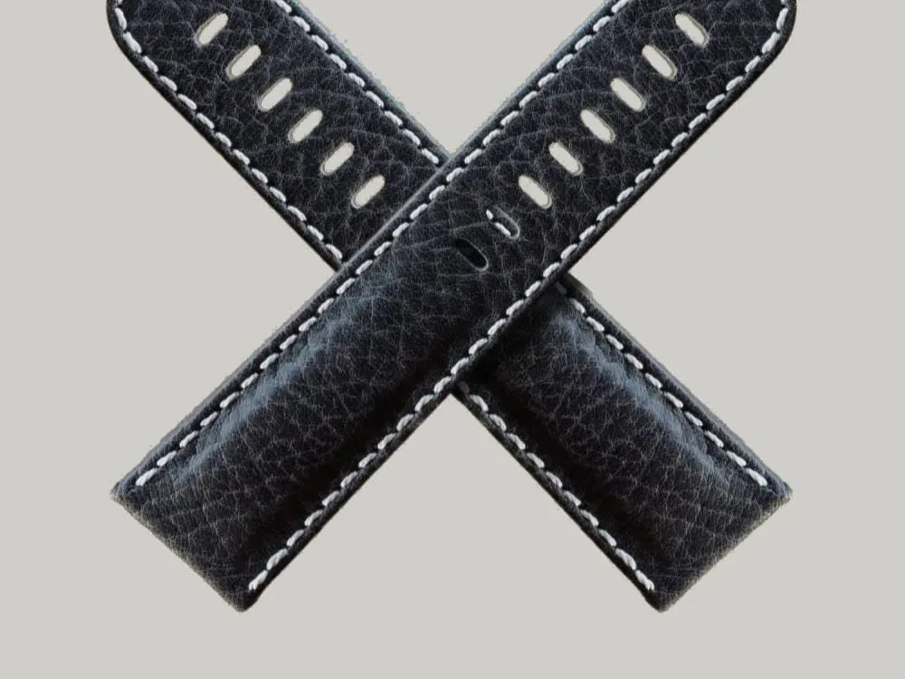 Two Black Buffalo watch straps with white stitching are crossed in an "X" shape against a light gray background. Each strap has multiple holes for adjustment.