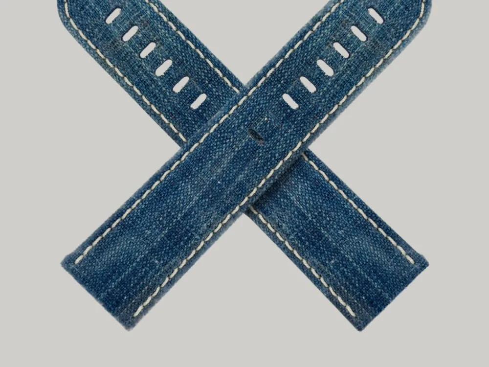 Two Japanese indigo watch straps crossed over each other. The straps are made of an indigo dyed Japanese Indigo canvas, with white stitching along the edges and multiple holes for adjusting the fit.