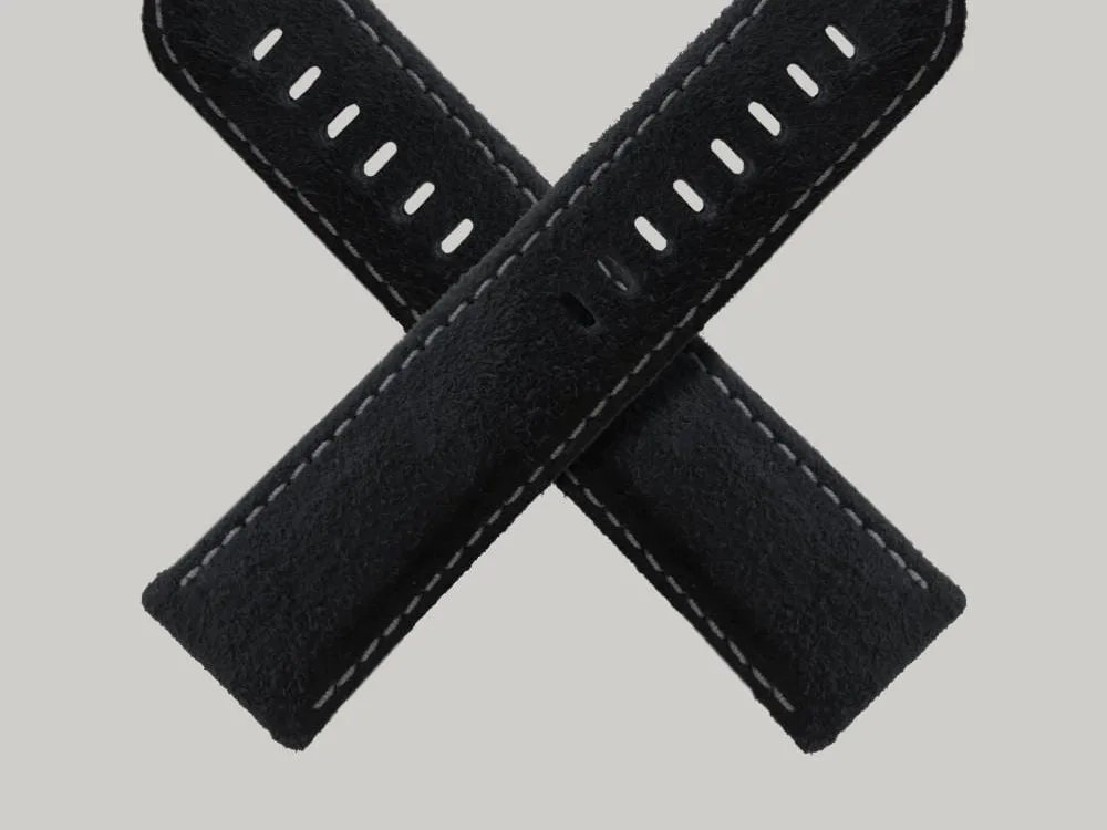 Two Rough-Out Suede watch straps crossed over each other in the shape of an "X" against a plain, light grey background. The straps have white stitching along the edges and multiple holes for adjustment.