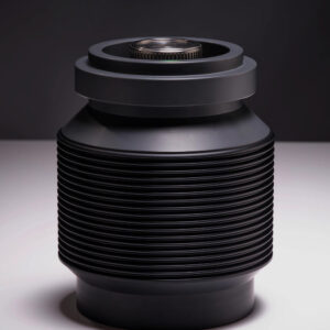 A modern, cylindrical black canister features multiple horizontal ridges and a smooth, flat top with a circular metallic component at the center. The dark background enhances the canister's sleek, industrial design.