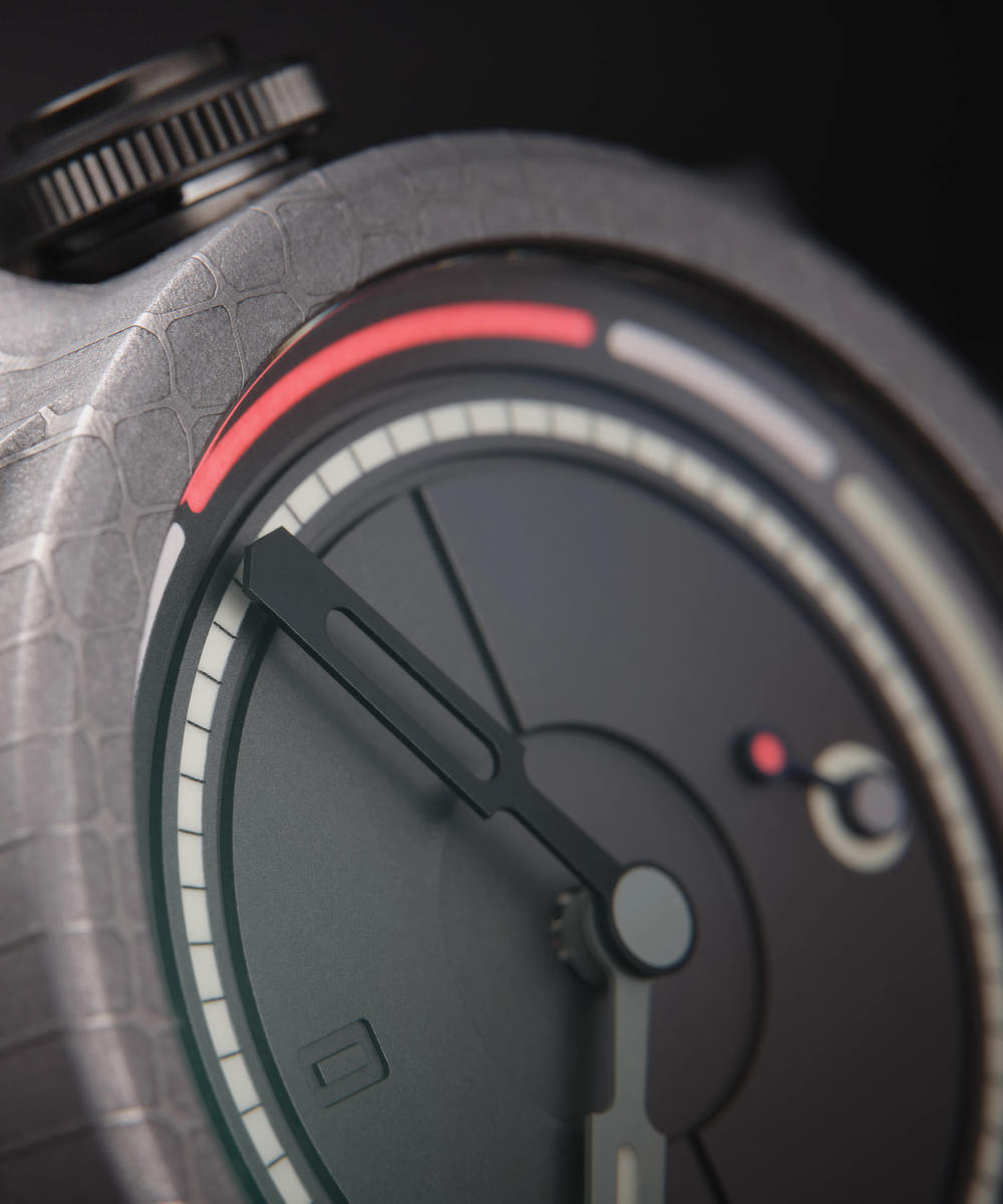 Close-up of a modern Obscura watch by Schofield. The face is predominantly black with red, white, and grey accents. The design is minimalistic with a small seconds sub-dial, and textured casing.