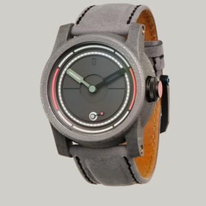 The Obscura with a grey textured fabric strap and a round black face. The watch has minimalistic markings, with a small circular red, white, and blue accent near the 6 o'clock position. The crown is black with red lume.