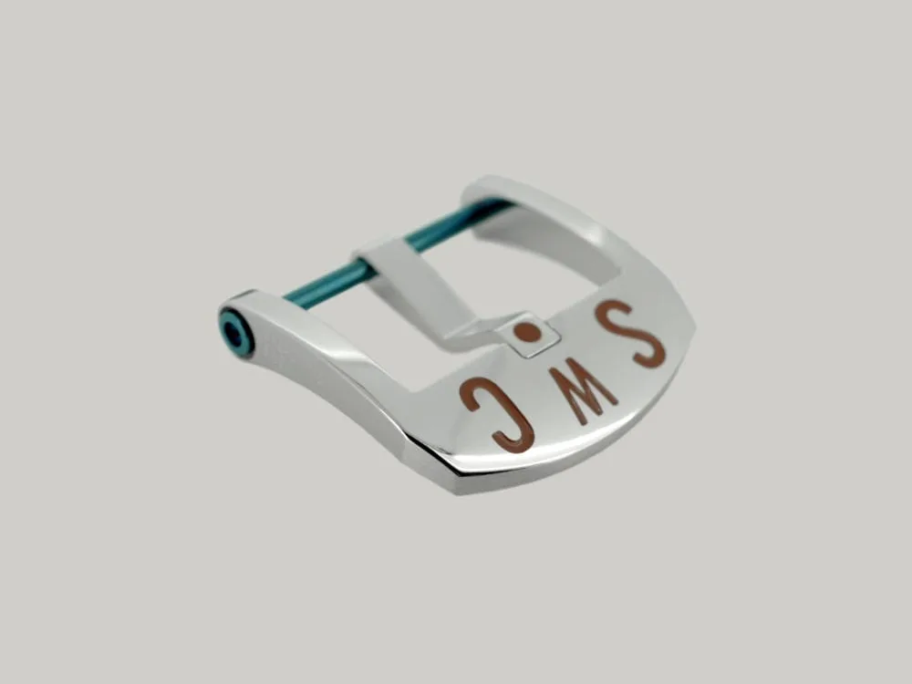 A Polished Steel BE Buckle with a blue PVD strap fitting screw. The thumbnail style buckle, called The Best Ever Buckle, features the engraved letters "SWC" in a red paint fill.
