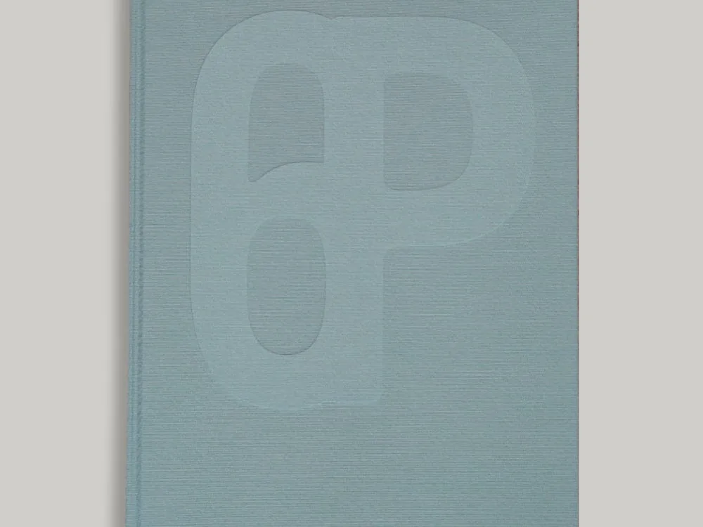 A light blue/green hardcover copy of Almanac ✦ 21 with an embossed abstract '6p' design and a pink ribbon bookmark.