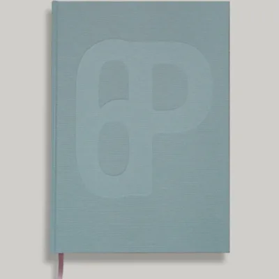 A light blue/green hardcover copy of Almanac ✦ 21 with an embossed abstract '6p' design and a pink ribbon bookmark.