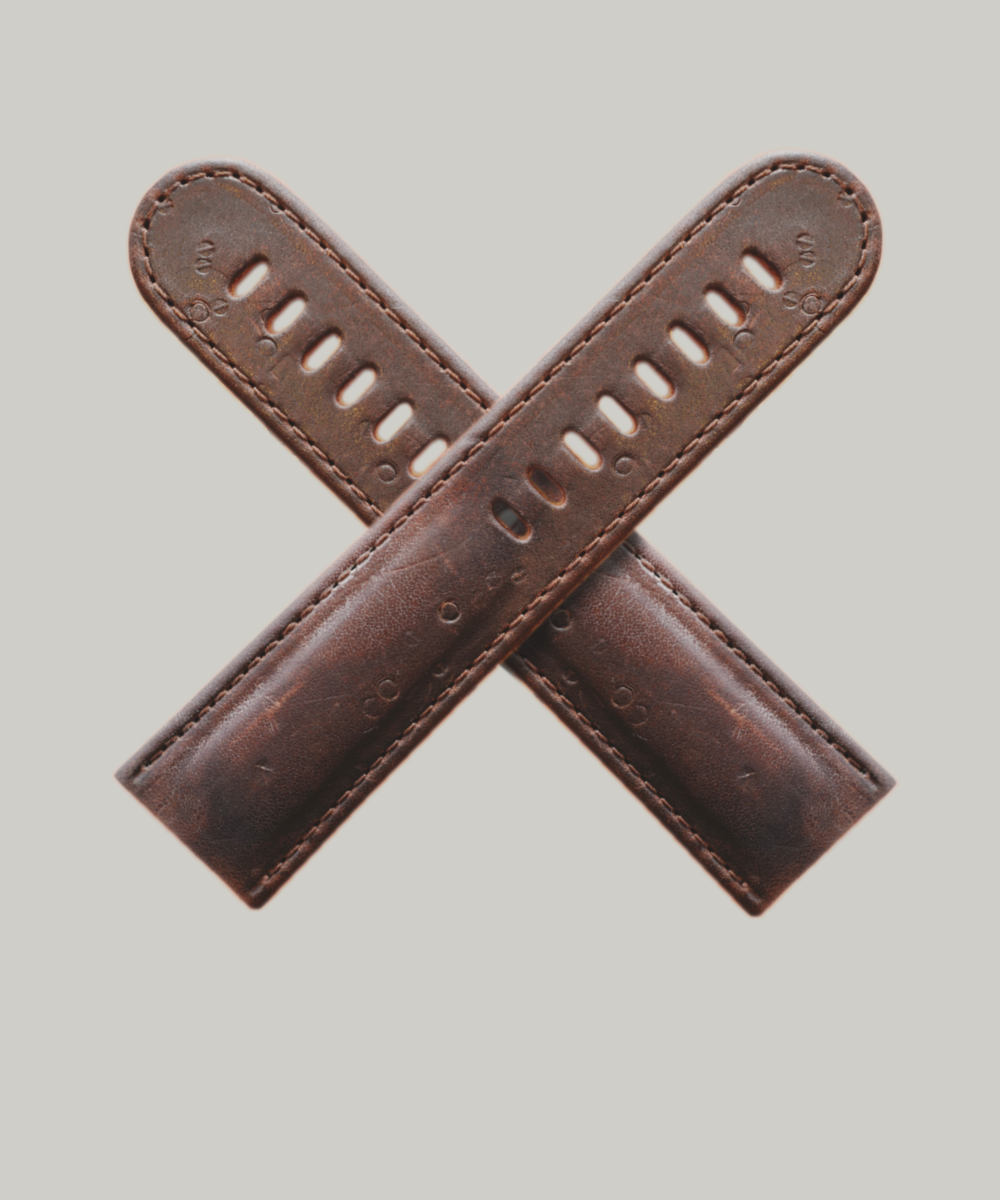 A pair of brown leather watch straps arranged in an "X" shape against a plain background. The straps have multiple holes for adjustment and visible stitching along the edges.