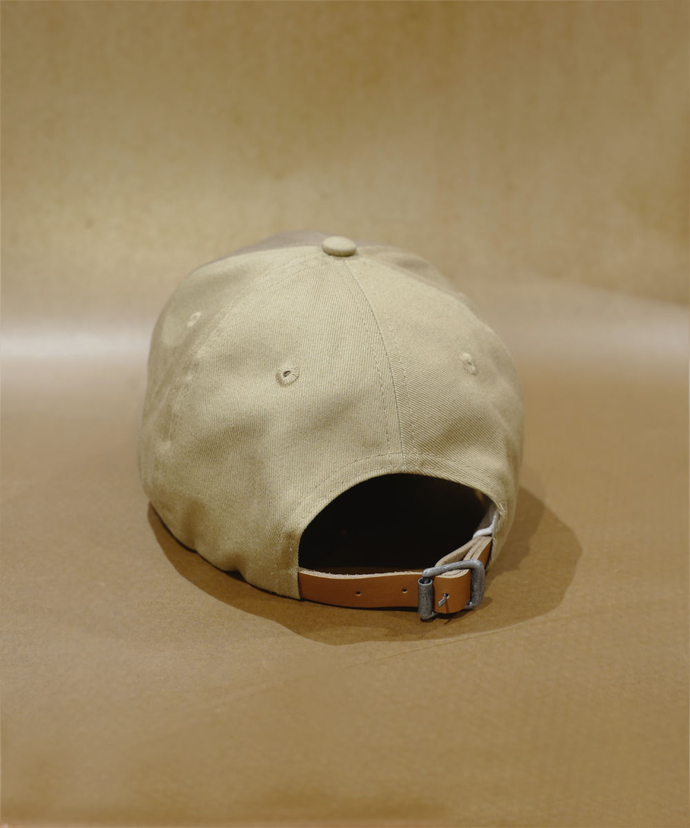 On a matching beige surface with a neutral background, the beige BAD MOOD CAP is displayed from the back. It features an adjustable strap with a metal buckle, highlighting its understated style.