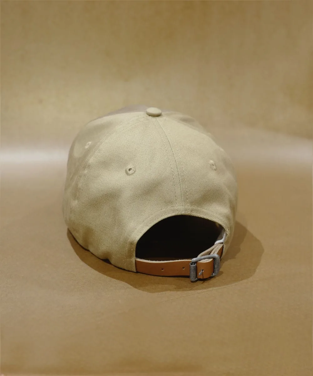 2024 PRODUCT TEMPLATE On a matching beige surface with a neutral background, the beige BAD MOOD CAP is displayed from the back. It features an adjustable strap with a metal buckle, highlighting its understated style.