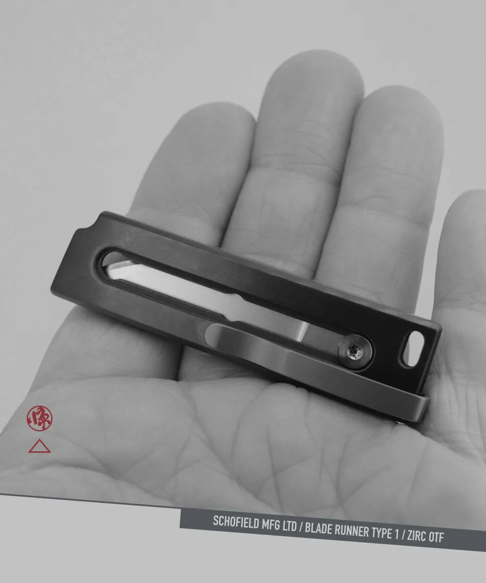 A person holds a compact, rectangular metal object with a slot and screw in the center. The background is a close-up of the person’s palm. Text at the bottom reads “SCHOFIELD MFG LTD / BLADE RUNNER TYPE 1 / ZIRC OTF.”.