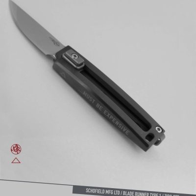 A sleek folding knife with a metallic blade and a dark handle, engraved with the words “MUST BE EXPENSIVE.” The knife is labeled as a Schofield MFG LTD Blade Runner Type 1 ZIRC OTF.