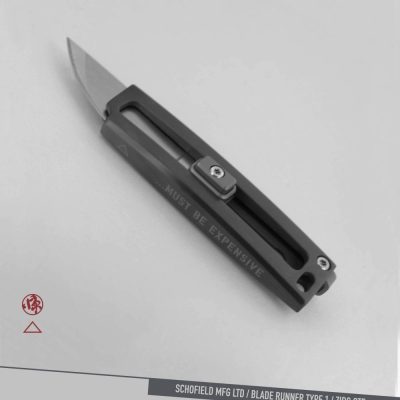 A sleek, modern folding knife with a metallic handle engraved with "MUST BE EXPENSIVE," displayed on a light gray background with branding text "SCHOFIELD MFG LTD / BLADE RUNNER TYPE I / ZIRC OTF" at the bottom.