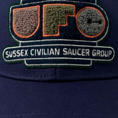 An indigo cap with chenille patch reading UFO Sussex Civilian Saucer Group