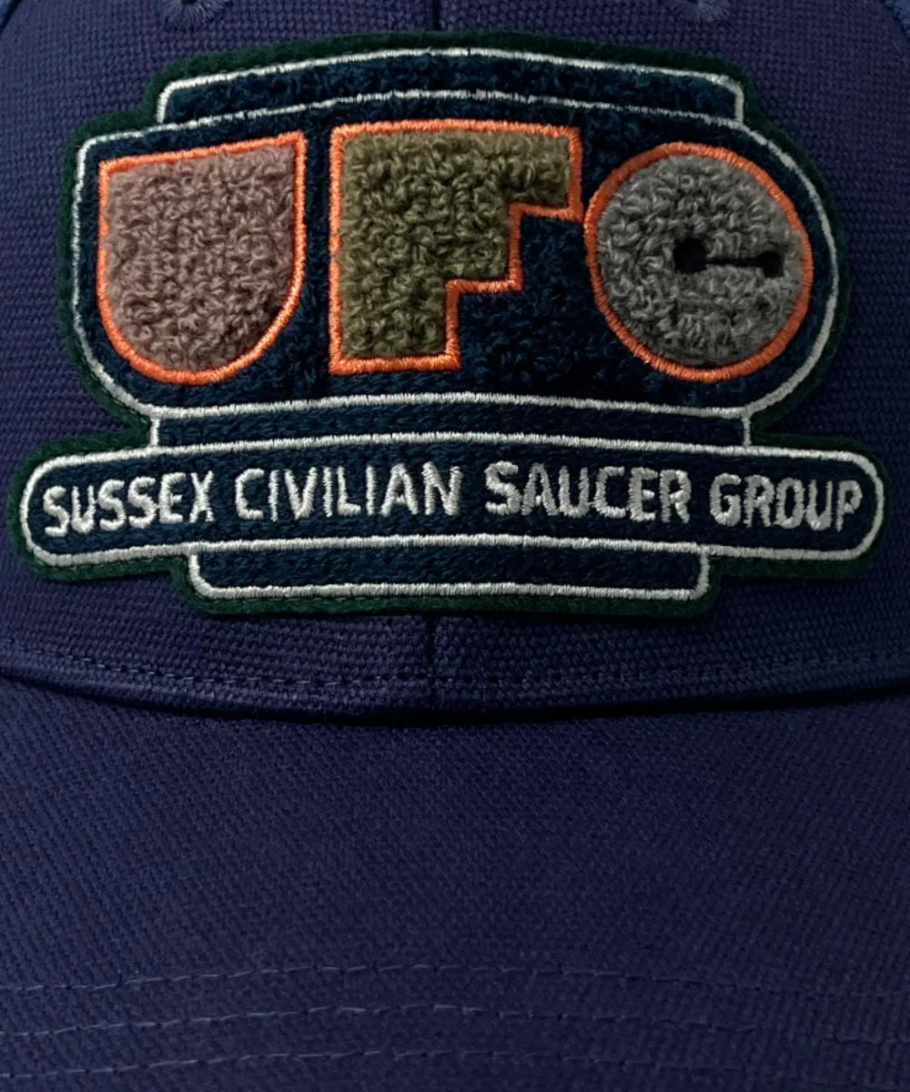 SCHOFIELD UFO PATCH CAP PATCH MAIN An indigo cap with chenille patch reading UFO Sussex Civilian Saucer Group