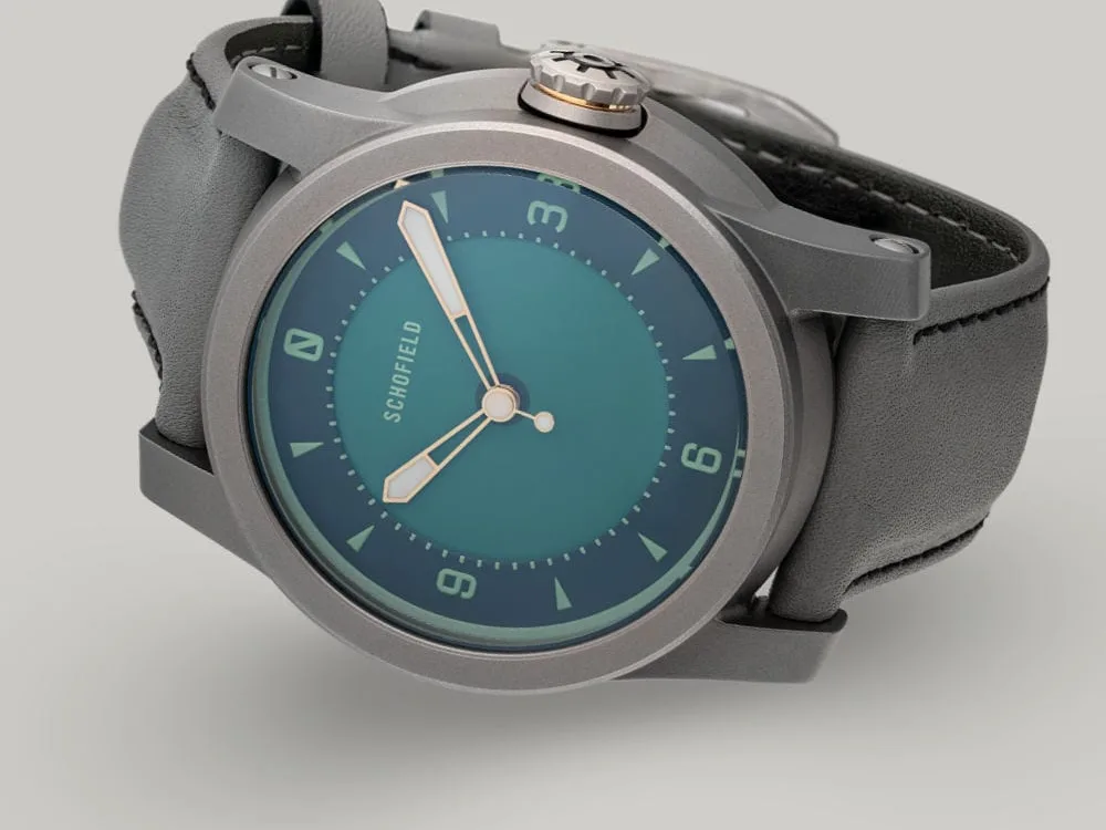 A grey titanium wristwatch with a green dial. The Strange Lights - NQR features custom lume on the Not Quite Green dial. Limited edition of 29 watches.