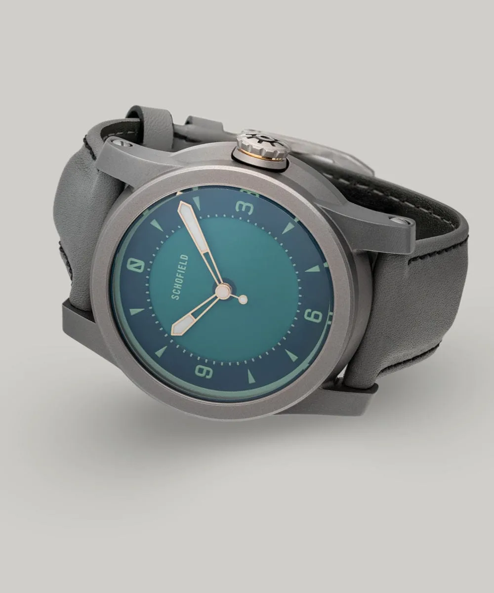 A grey titanium wristwatch with a green dial. The Strange Lights - NQR features custom lume on the Not Quite Green dial. Limited edition of 29 watches.