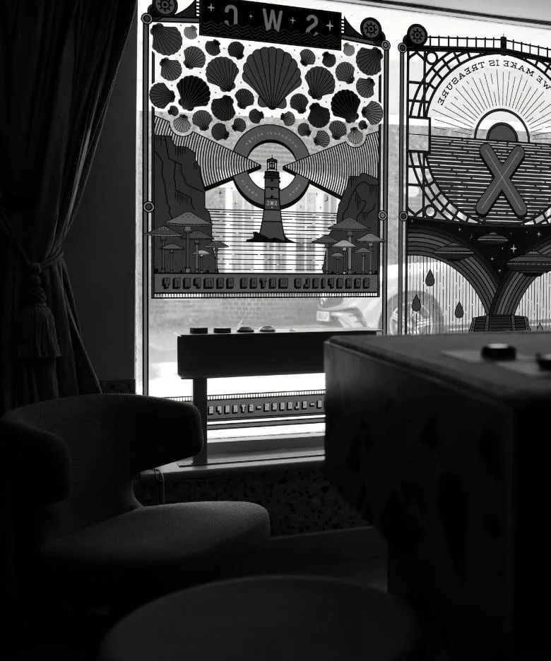 A black and white view of the Schofield's Sussex shop front from the inside, with decorative window illustrations