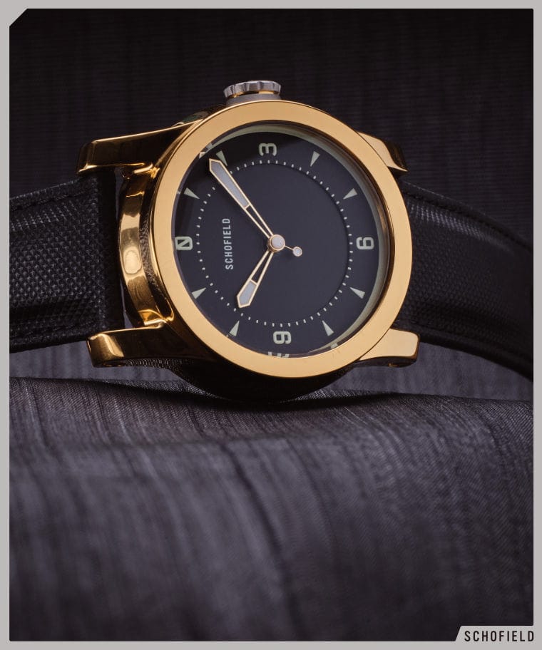 A minimal black dialed watch with a gold case
