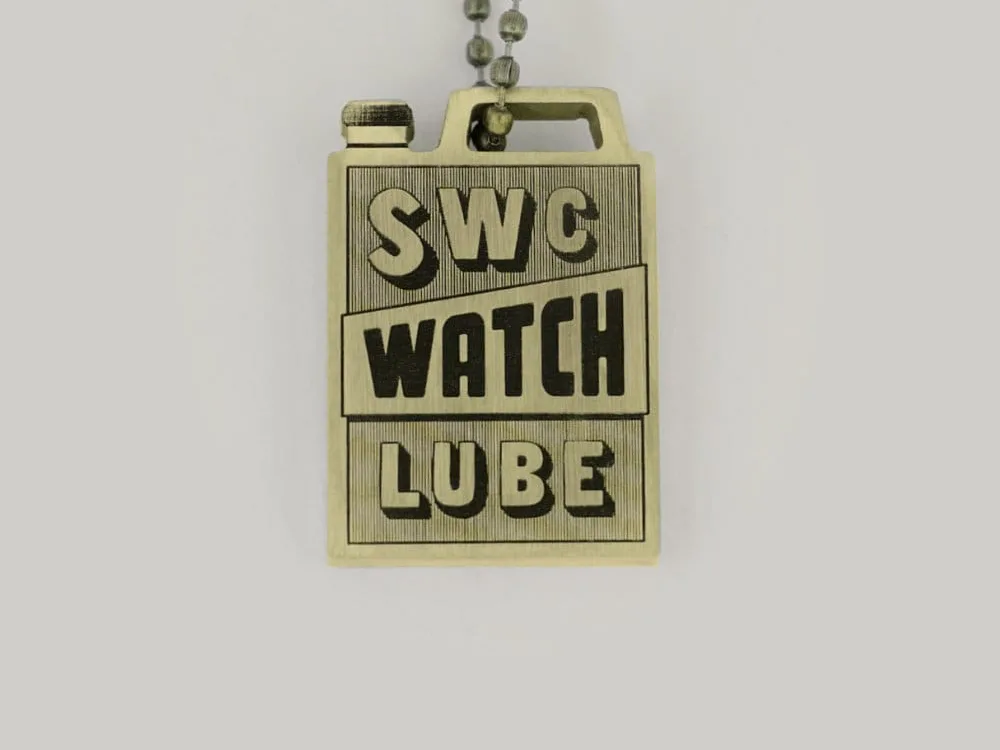 A brass Schofield keyring that reads SWC Watch Lube