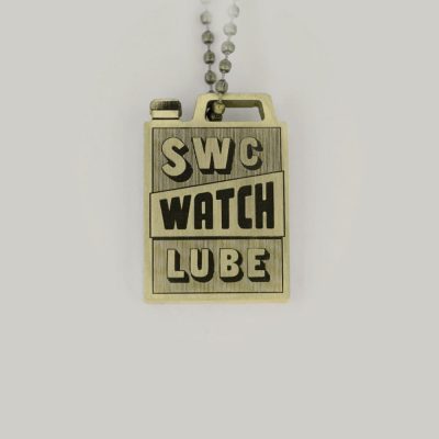 A brass Schofield keyring that reads SWC Watch Lube
