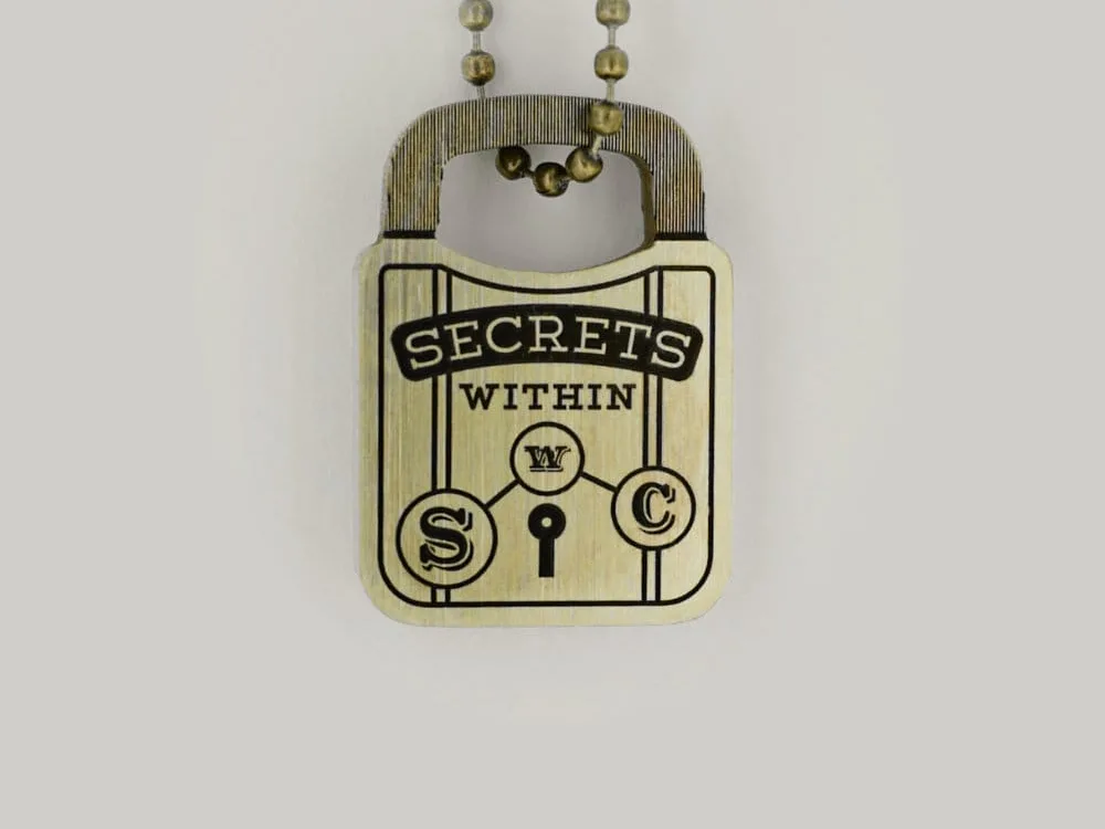 A brass Schofield padlock design keyring that reads Secrets Within