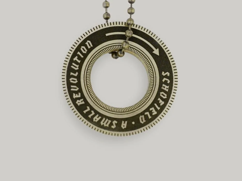 A brass Schofield keyring that reads Schofield A Small Revolution