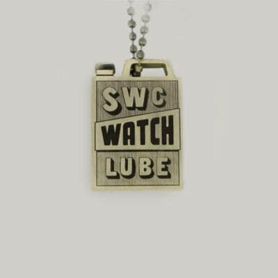 A brass key ring in the shape of an oil can with SWC watch lube written on it