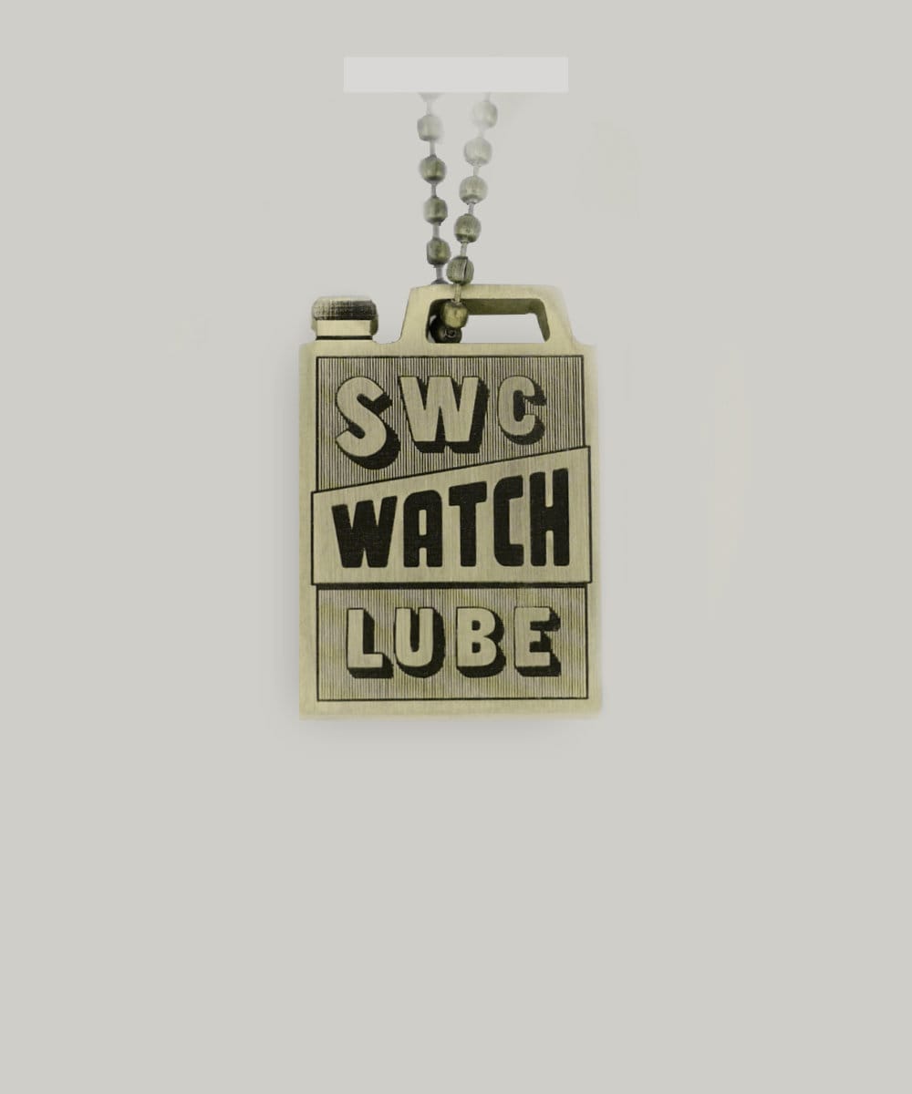 A brass key ring in the shape of an oil can with SWC watch lube written on it