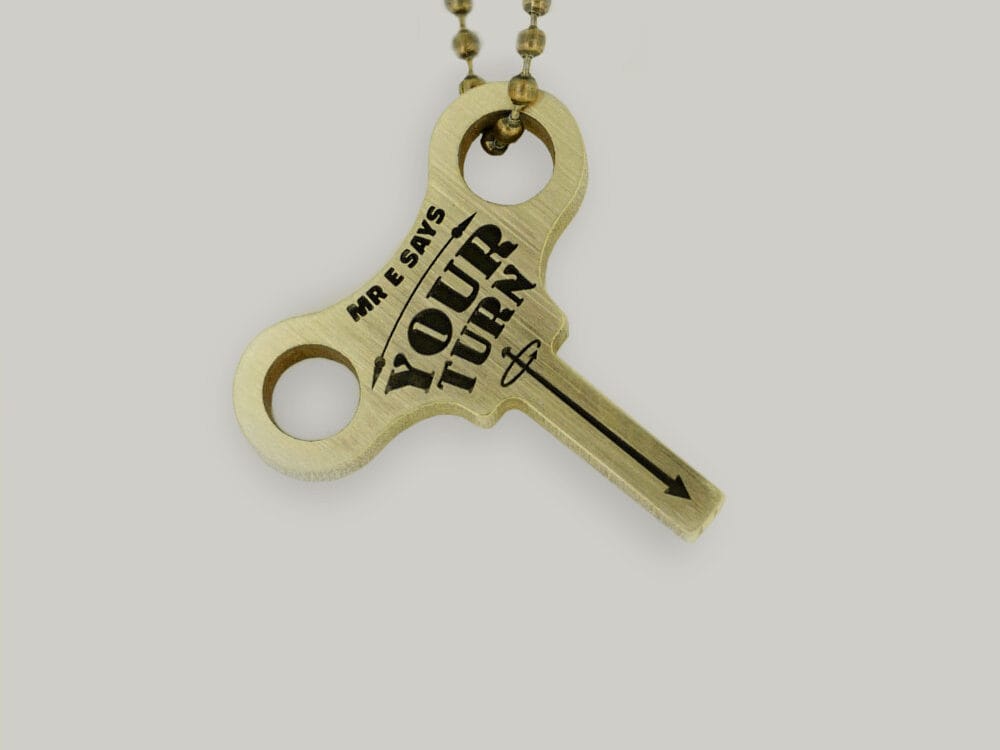 Key-shaped brass key ring Schofield made a brass keyring with "Mr. E says your turn" in the shape of a clock winding key.