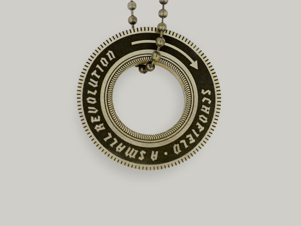 Wheel-shaped brass key ring Brass key ring shaped like a wheel that says "Schofield: A Small Revolution"