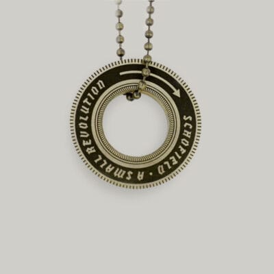 Wheel-shaped brass key ring Brass key ring shaped like a wheel that says "Schofield: A Small Revolution"