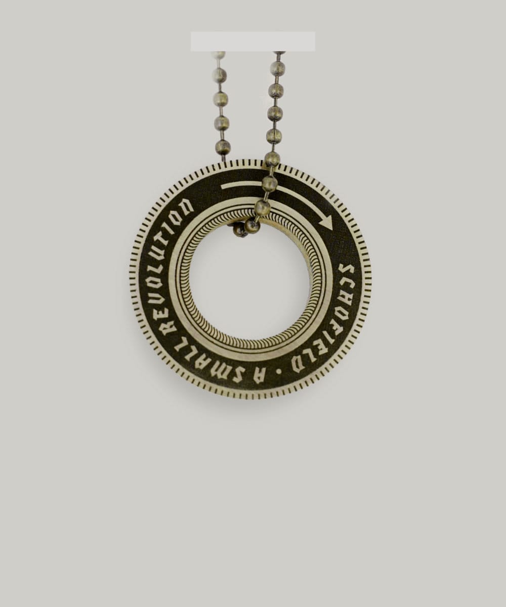 Brass key ring shaped like a wheel that says "Schofield: A Small Revolution"