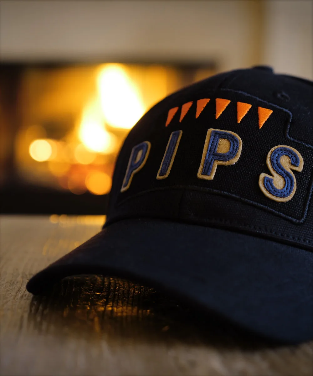 Schofield Six Pips black Cap in moody lighting.